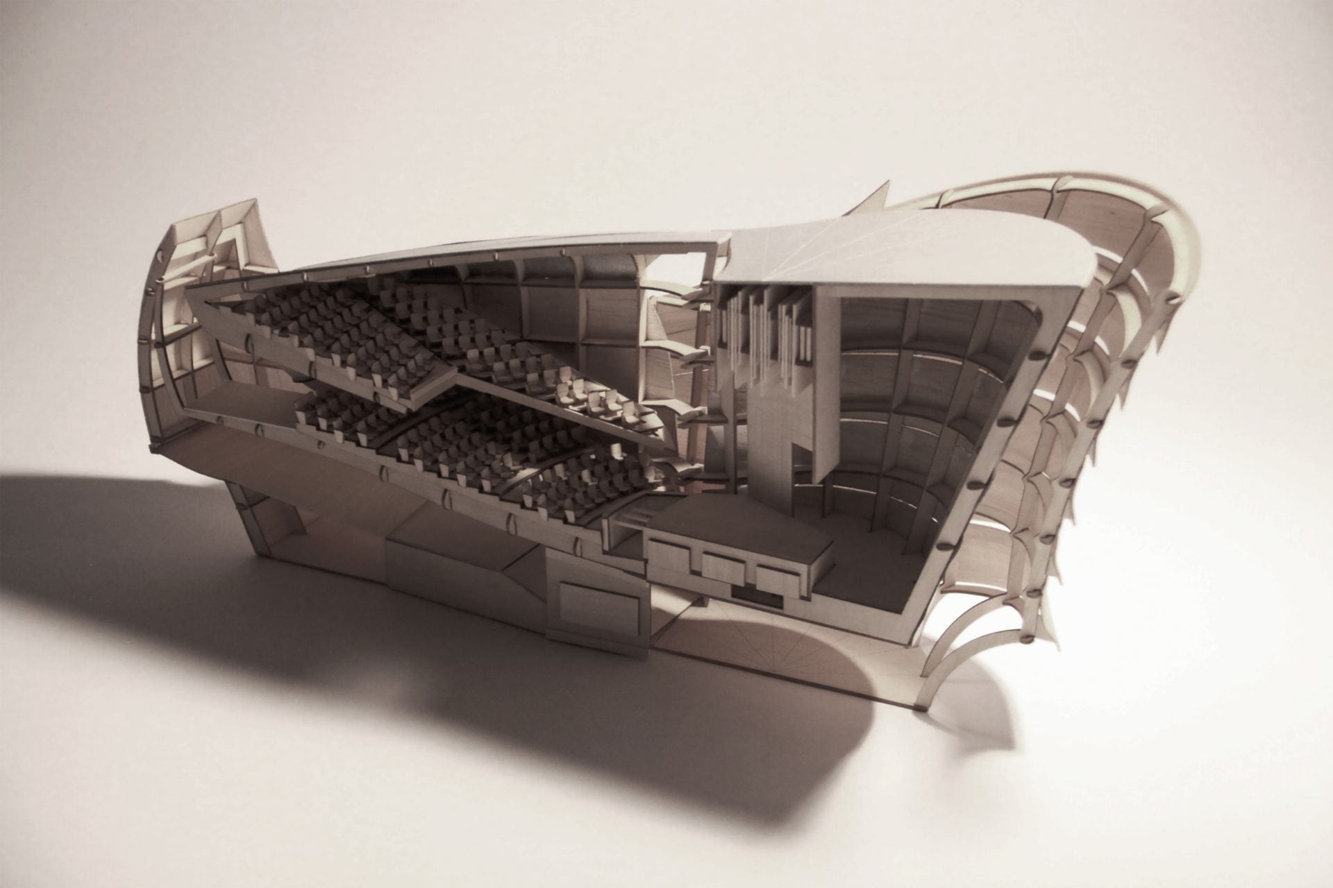 A scale model vertical section cut of a theater with an elegant curved exterior envelope.